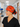 A woman in a hospital hallway wearing a bright orange Halloween-themed scrub cap with cartoon skeletons and the text 'I FOUND THIS MEMORABLE', paired with black scrubs.
